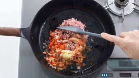 Sautéing grated aromatics and ground pork for miso ramen base.