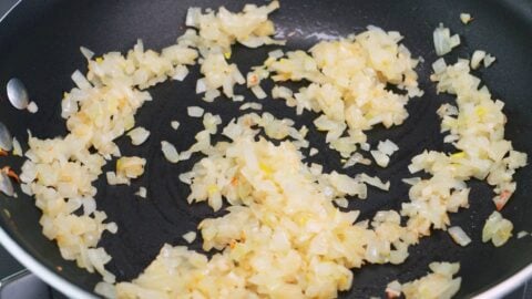 Browning onions and garlic in a frying pan for taco rice.