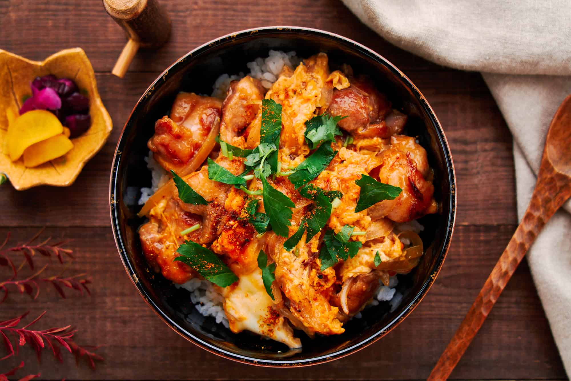 Overhead view of the Oyakodon bowl, revealing the balance of golden eggs, juicy hunks of chicken, and glistening sauce over a bed of steaming hot rice.
