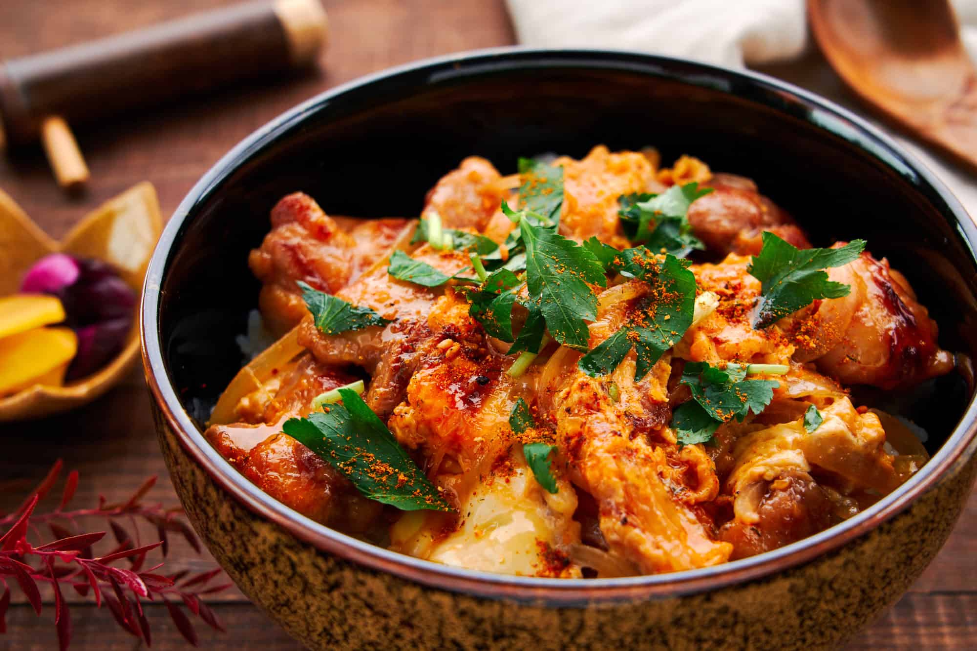 Close-up shot of Oyakodon, showcasing tender chicken pieces nestled amidst creamy, half-set eggs atop a bed of steamed rice.
