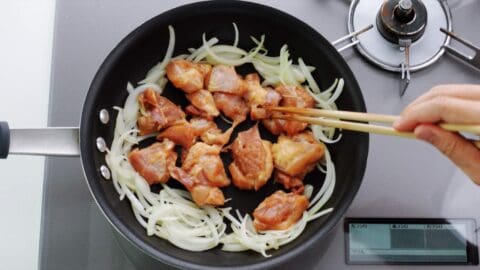 Browning chicken in a frying pan with onions.