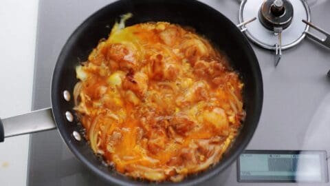 Redistributing egg in a pan of oyakodon by shaking it.