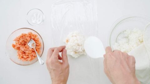 Covering salmon with more rice.