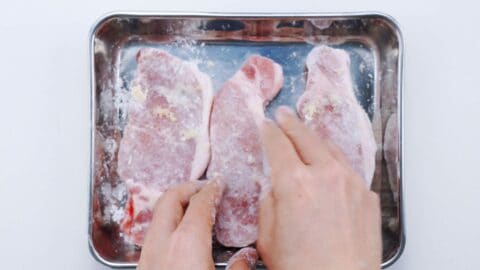 Dusting Japanese pork chops with potato starch.