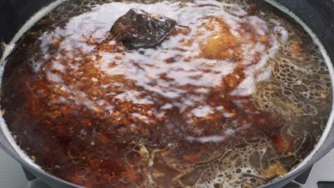 Soy sauce ramen broth simmering in a pan.