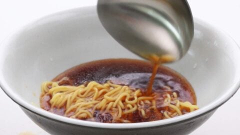 Serving shoyu ramen broth over noodles.