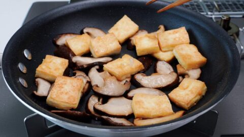 Shiitake mushrooms and tofu in a frying pan.