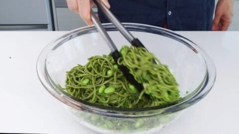 Tossing soba salad with edamame, scallions and sesame dressing.