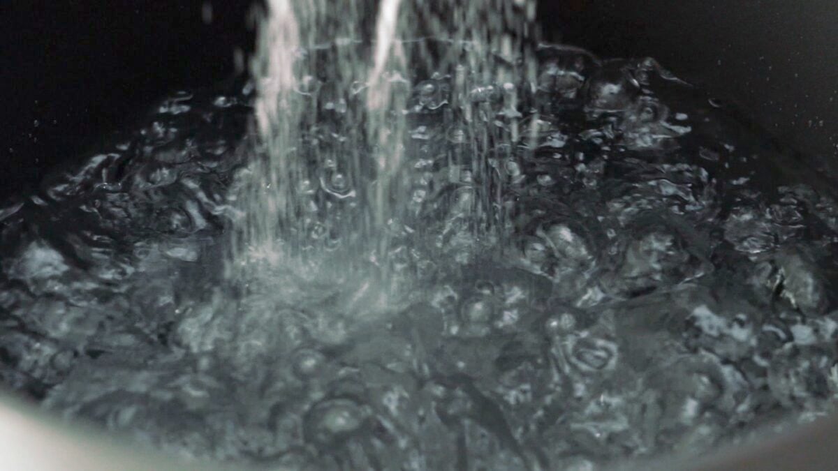 Salting a big pot of boiling water for the spaghetti.