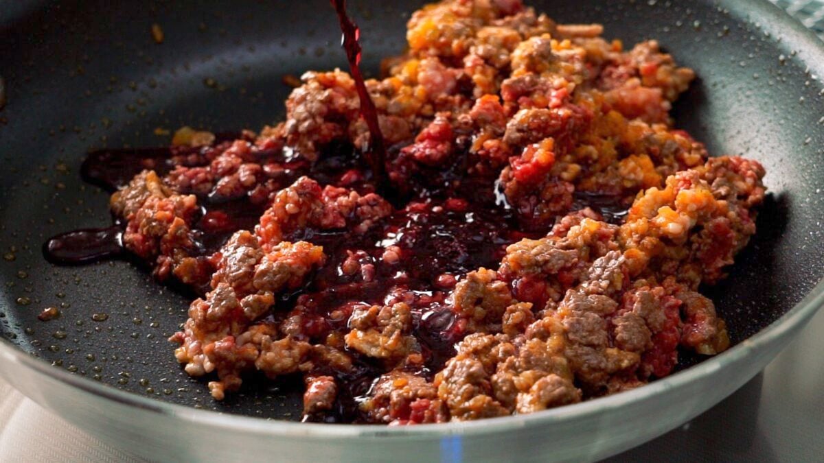 Red wine being added to the meat sauce.