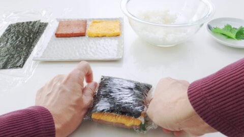 Wrapping Japanese rice sandwich with plastic wrap.