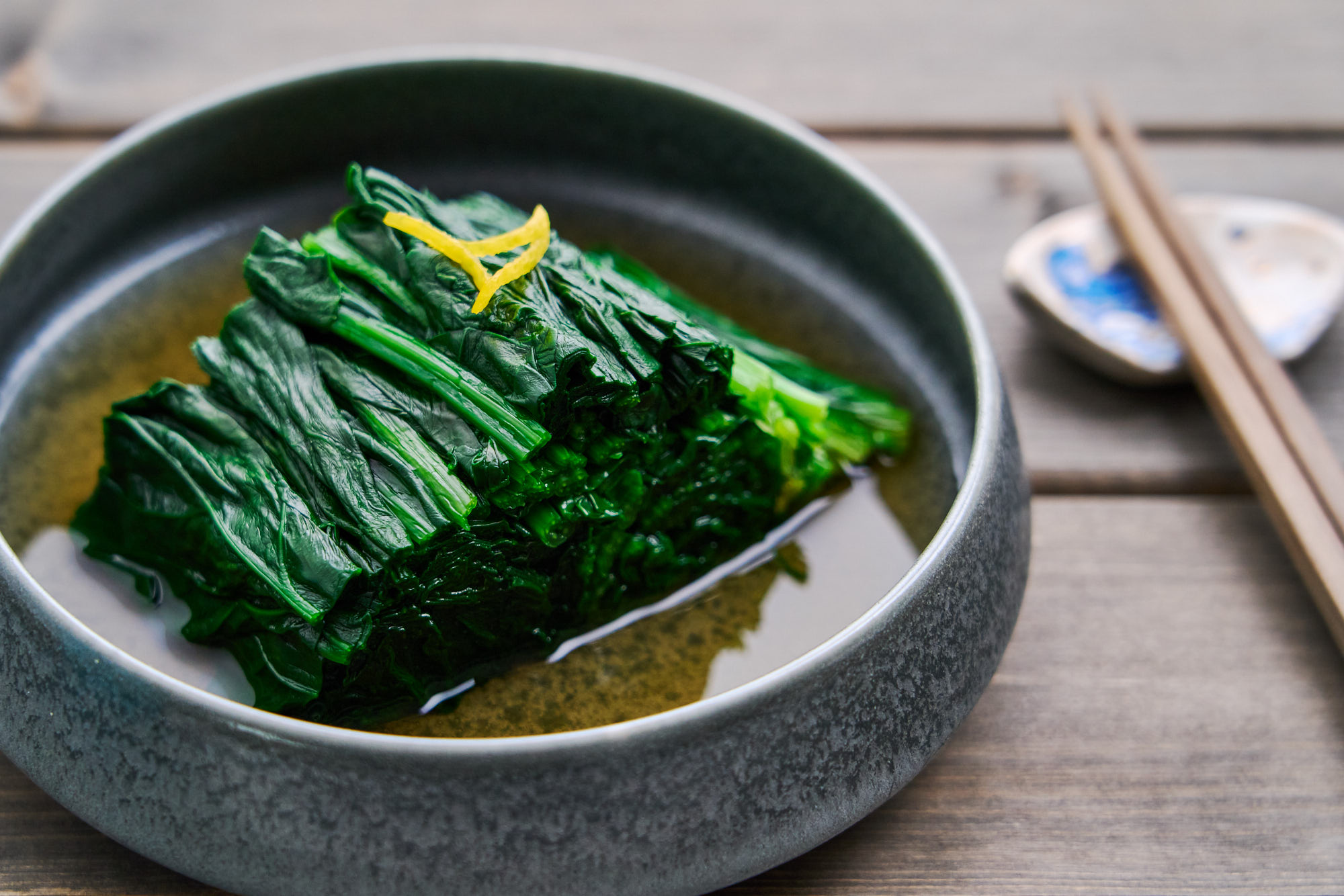 Bright green spinach arranged in a neat bundle infused with golden dashi broth.