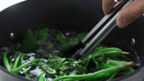 Stirring spinach as it boils.