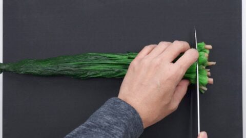 Trimming roots off boiled spinach.