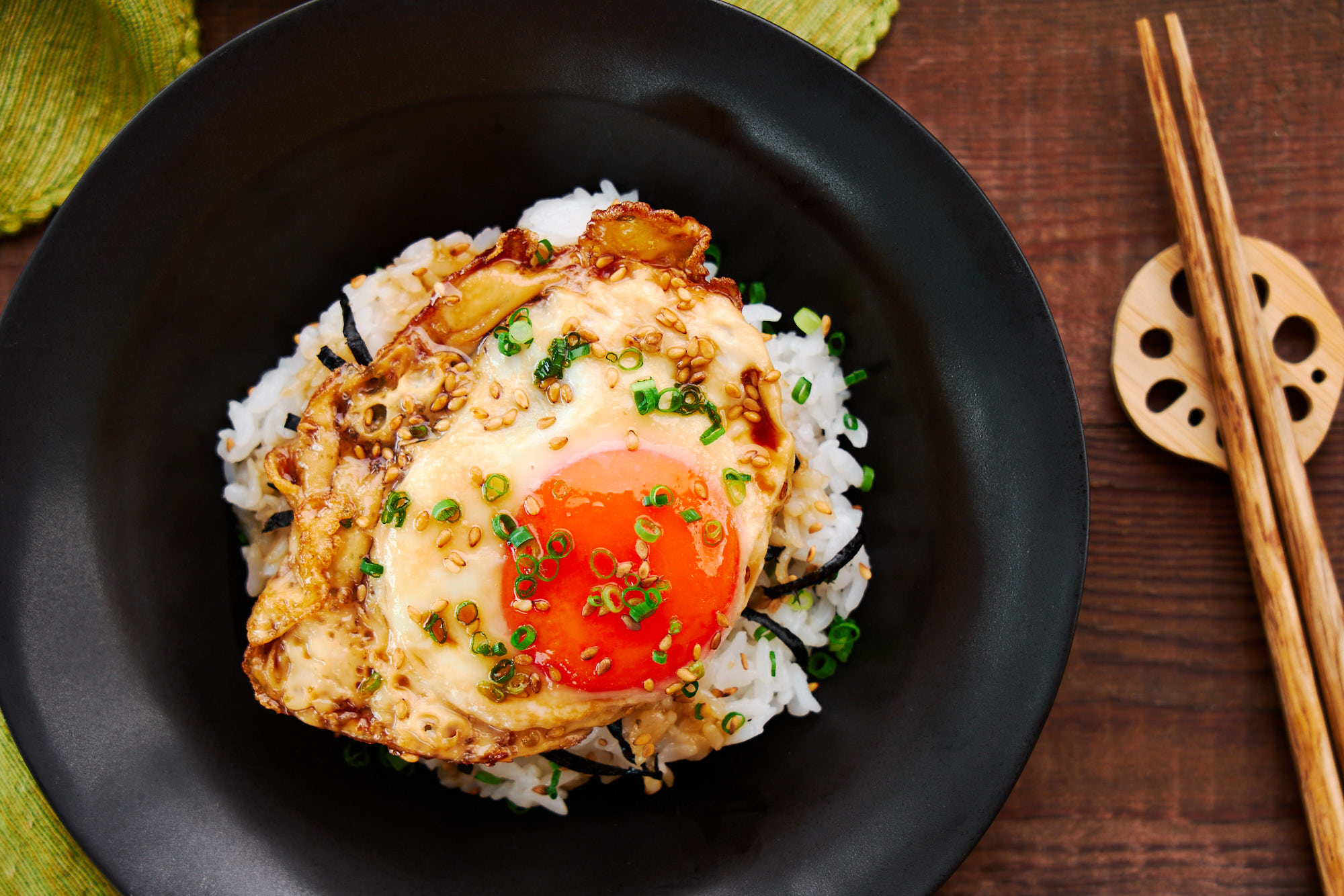 Overhead view of a fried egg glazed in savory sweet teriyaki sauce over rice.