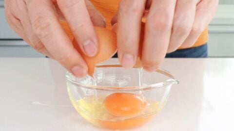 Breaking and egg into a glass bowl.