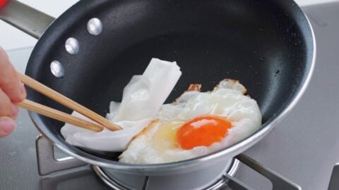 Removing excess oil from the pan before adding teriyaki sauce.