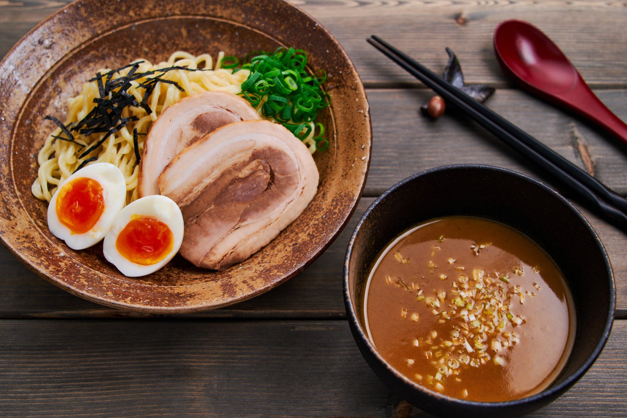 Ramen dipping sauce (tsukemen broth) with a bowl of thick ramen noodles and toppings.