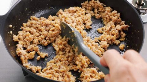 Cooking ground pork with onions, carrots, garlic and ginger.