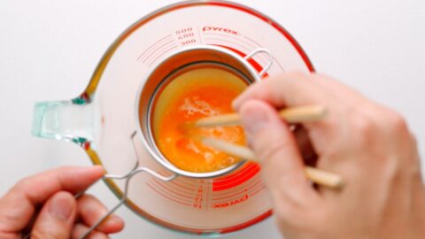Straining eggs through sieve to remove bubbles.
