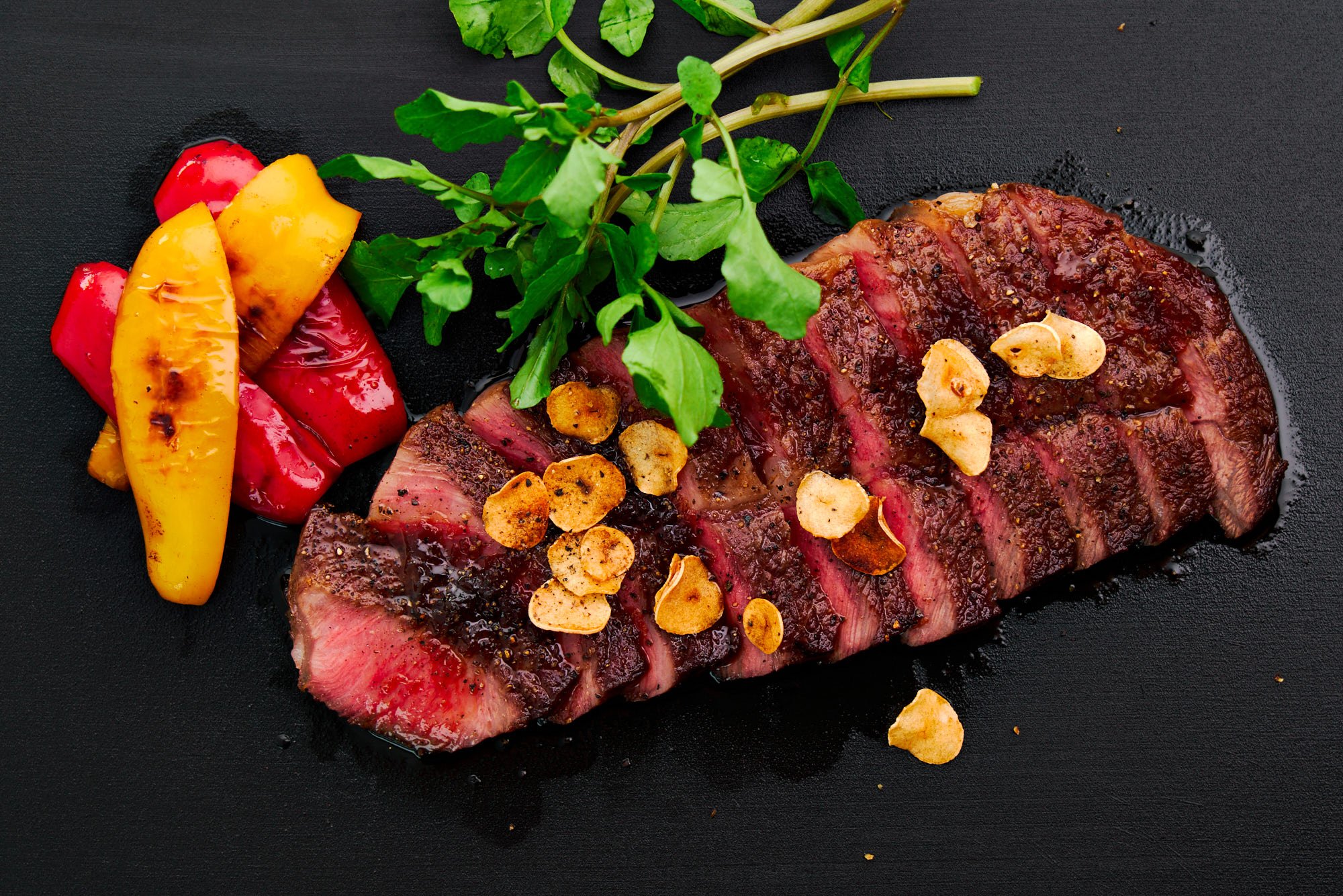 Overhead view of a sliced homemade Japanese wagyu steak topped with garlic chips.