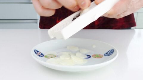 Slicing garlic on a mandoline to make garlic chips.
