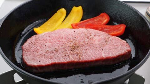 A5 wagyu steak in a cast iron skillet with peppers.