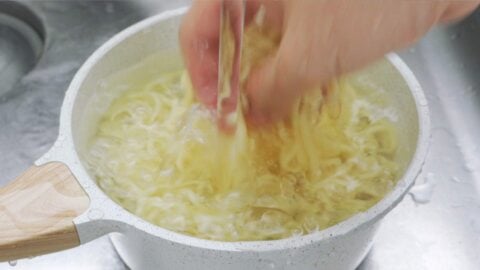 Rinsing cooked yakisoba noodles in cold water.