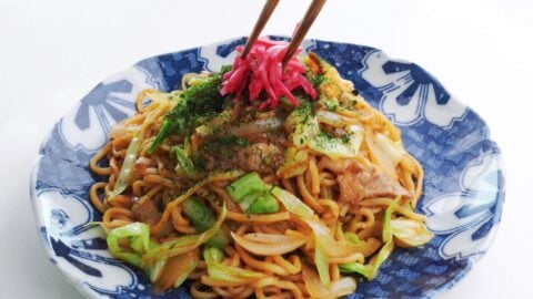 Plating yakisoba noodles with red pickled ginger.