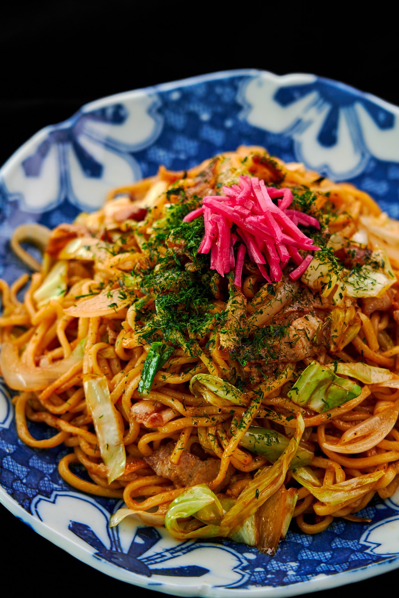 A plate of homemade Japanese yakisoba (stir-fried ramen noodles) with pork cabbage, onions and benishoga (red pickled ginger).