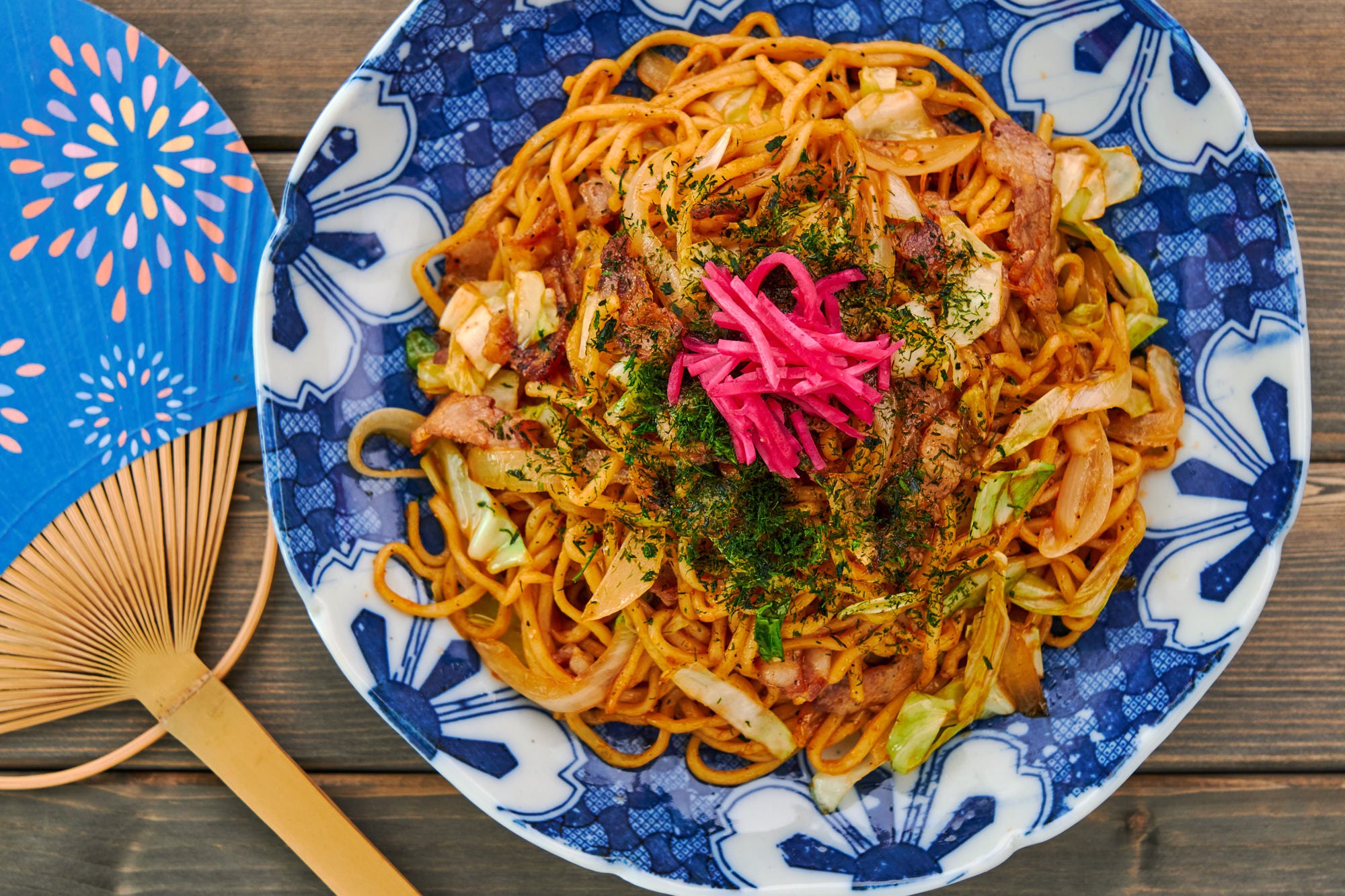 Overhead view of a summer scene in Japan with a plate of festival style yakisoba noodles.